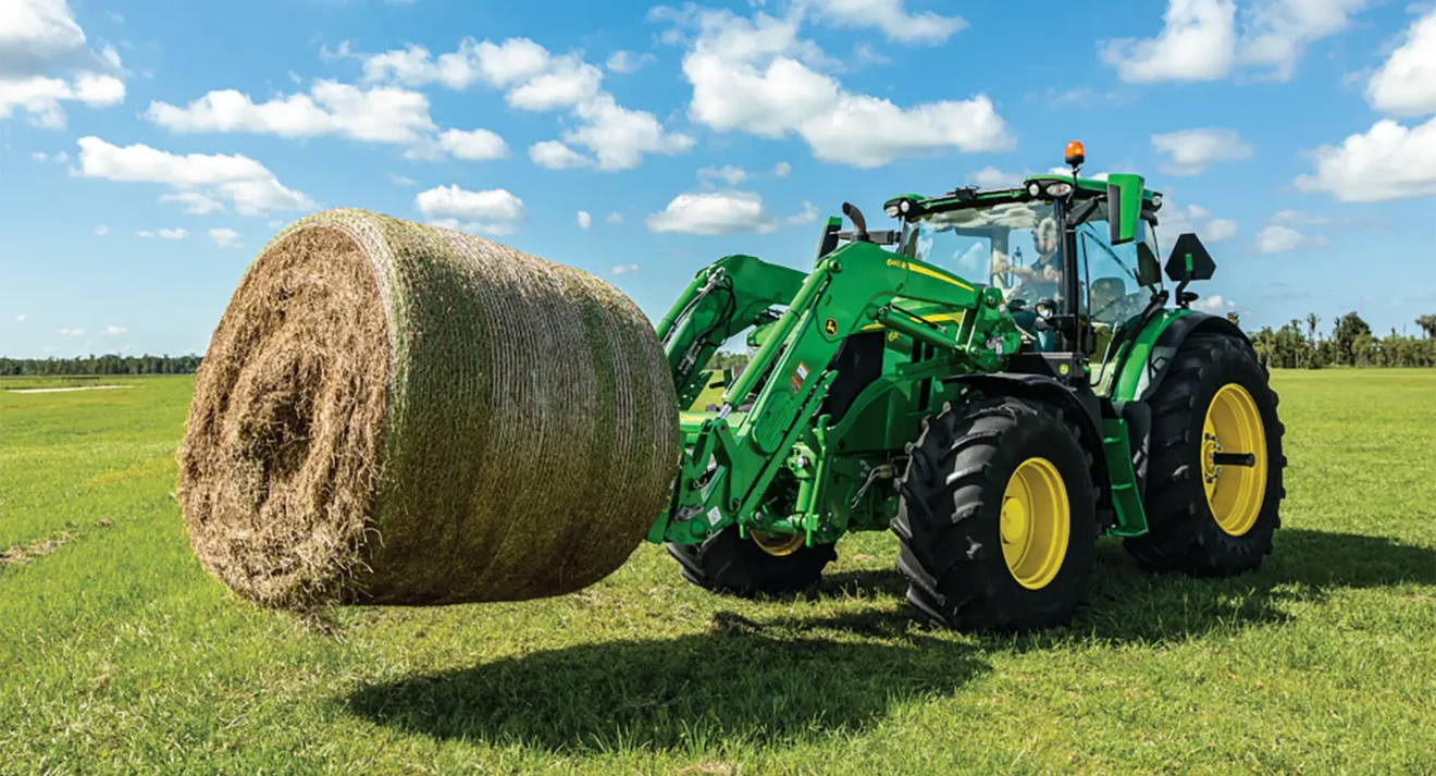John Deere 6 Series tractor holding a hay bale