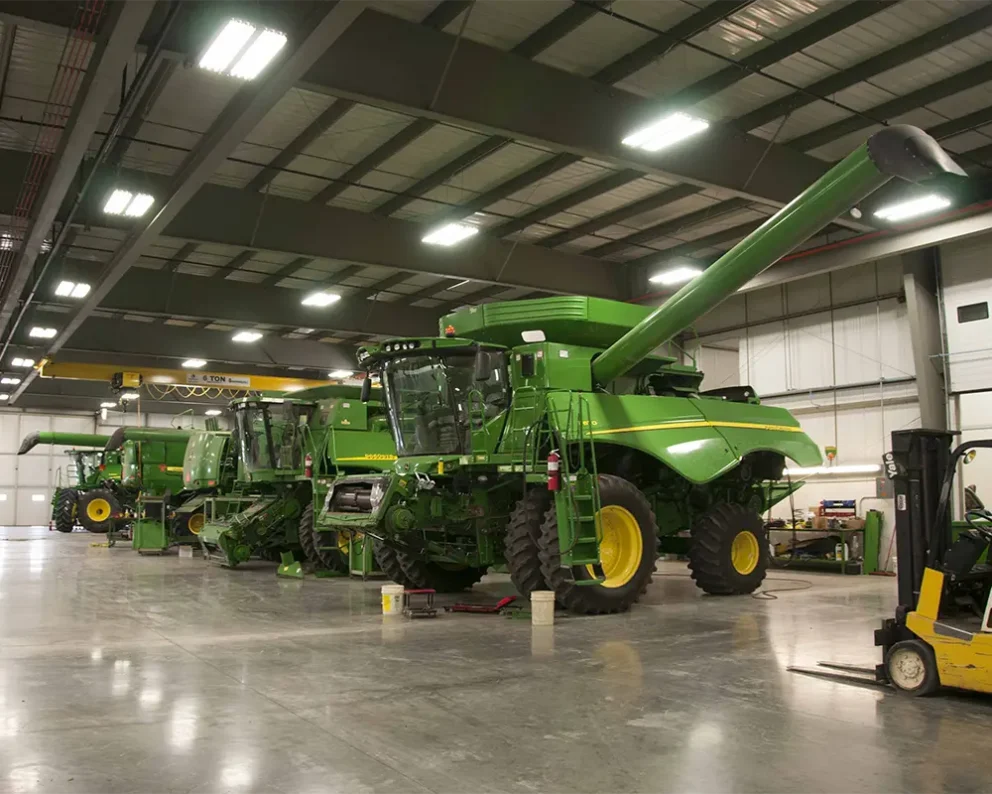 Multiple large farming machines in a well-lit garage