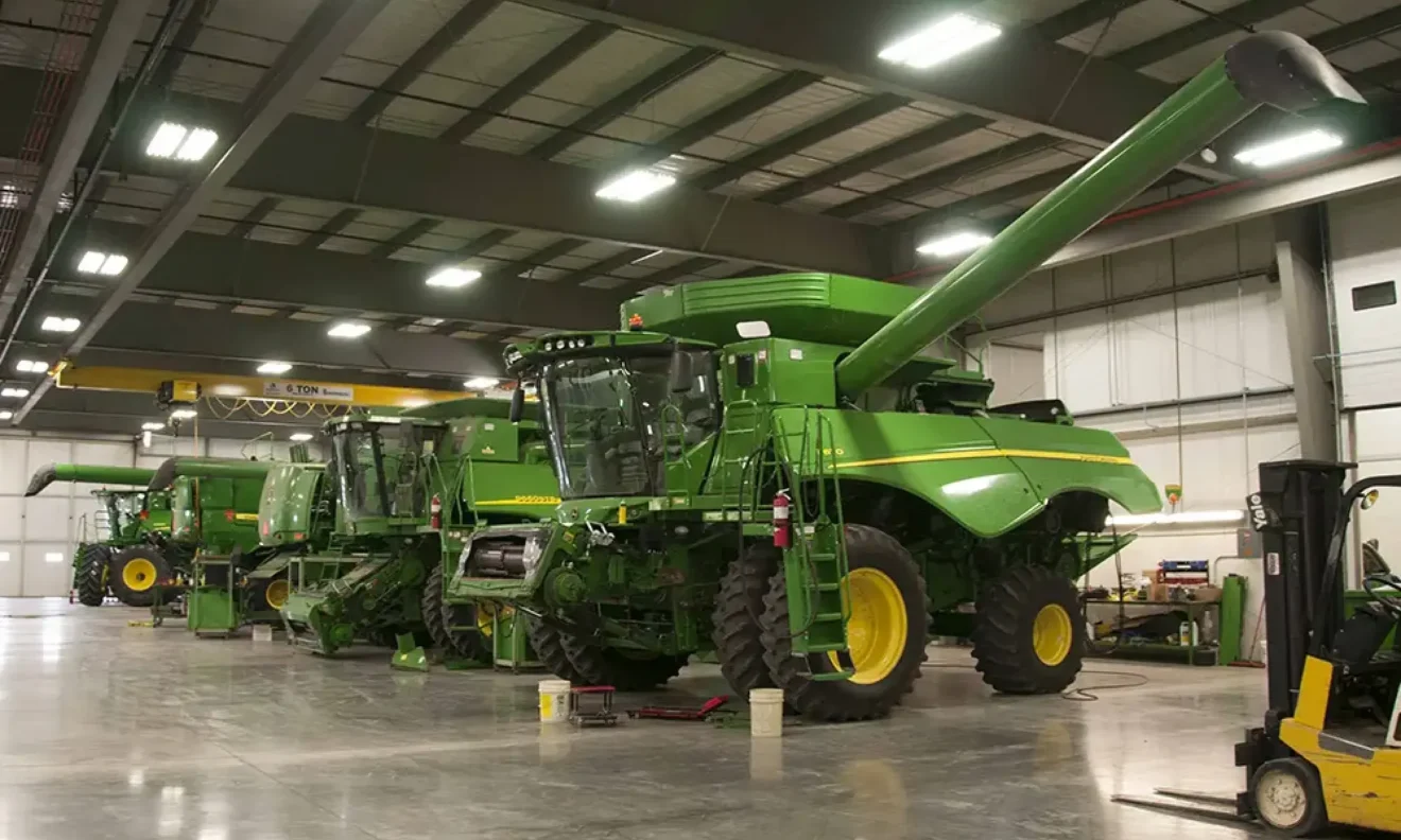 Multiple large farming machines in a well-lit garage